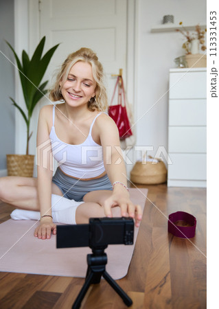 Vertical shot of athletic, fitness woman recording video of herself on digital camera, creating content for social media about workout and home exercises Vertical shot of athletic, fitness woman recording video of herself on digital camera, creating content for social media about workout and home exercises 113331453