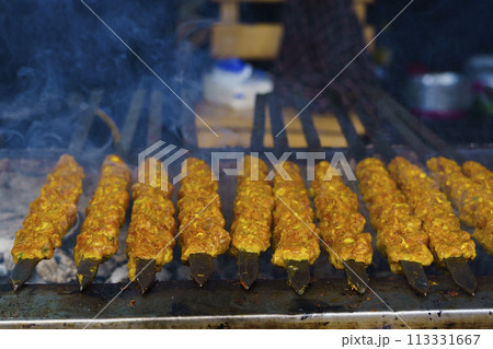 Skewers of shish kebab and chicken cooked on a grill near Ampel area in Surabaya, Indonesia. 113331667