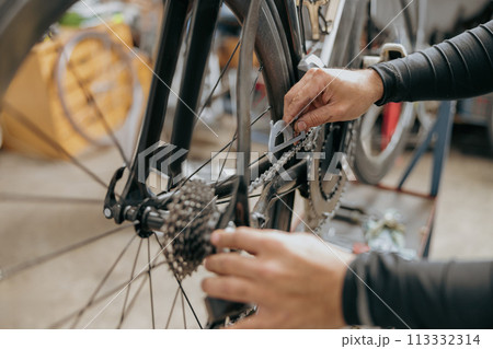 Cropped shot of male mechanic working in bicycle workshop. Bike service, repair and upgrade 113332314