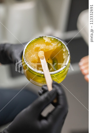 Orange body scrub with sugar and oil in glass jar in female hand. Homemade cosmetic for peeling and spa care. Copy space and empty place for advertising 113332691