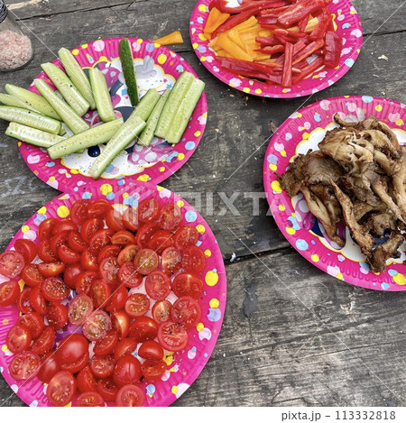 Colorful plates with vegetables and mushrooms on a wooden surface at a picnic 113332818