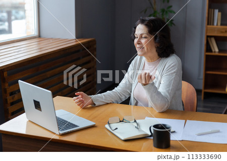 Happy middle aged senior woman sit with laptop talk on video call with friends family. Laughing mature old senior grandmother having fun talking speaking with grown up children online Happy middle aged senior woman sit with laptop talk on video call with friends family. Laughing mature old senior grandmother having fun talking speaking with grown up children online 113333690