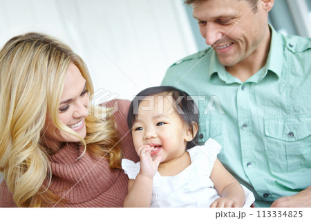 Shes captured their hearts. A happy couple spending time with their beautiful adopted daughter while at home. 113334825
