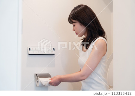 トイレットペーパーを引っ張る若い女性 113335412