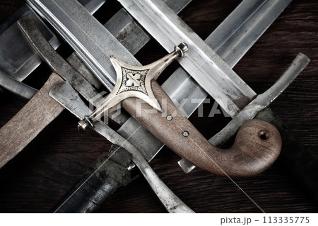 Swords and sabre on wooden background. 113335775