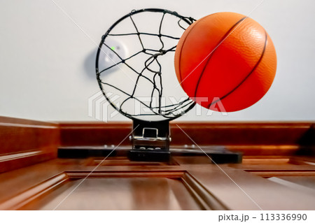 Selective focus on the netting of a miniature toy basketball hoop on the door of a bedroom. Selective focus on the netting of a miniature toy basketball hoop on the door of a bedroom. 113336990