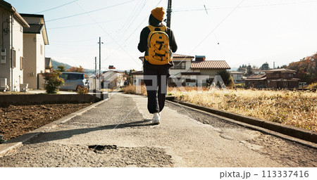 Woman, walk in street and travel with backpack in neighborhood, adventure on holiday or commute. Back view, journey and traveller on road with bag in residential area for vacation or weekend trip 113337416