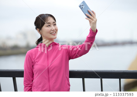 スマホで写真を撮るスポーツウエアのミドル女性 スマホで写真を撮るスポーツウエアのミドル女性 113337593