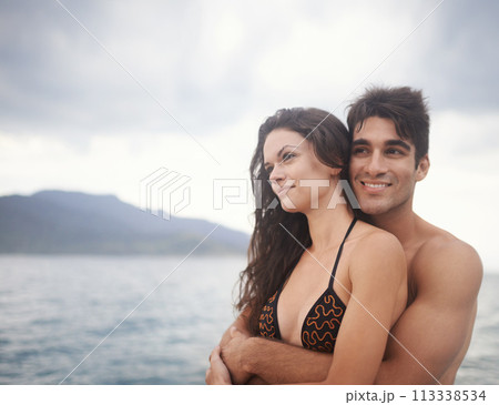 Couple, embrace and travel to ocean on holiday, love and relax by water on adventure. Happy people, peace and bonding for relationship in outdoors, support and hug on weekend trip to sea or nature 113338534