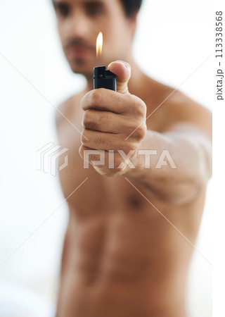 Hand, lighter and fire with a man in studio on a white background for heat or flame closeup. Gas, glow and hot with the body of a shirtless person holding a burning light for orange and warmth 113338568