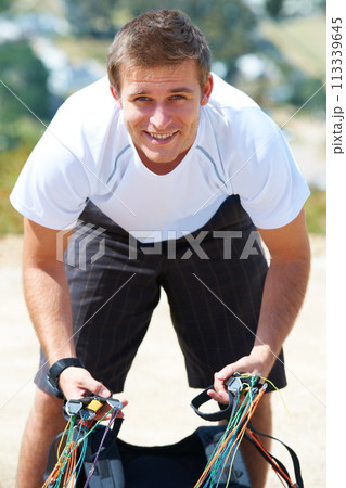 Paragliding, parachute or man in sport for portrait, smile or strings for exercise for flight preparation. Athlete, face or happy with fitness for outdoor wellness, helmet or equipment in countryside 113339645