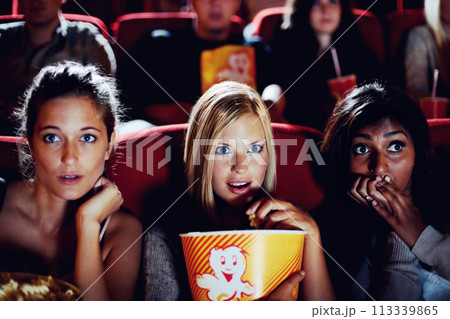 Wow, popcorn and women in the cinema watching a movie for entertainment while eating a snack. Face, expression and food with shocked young friends in a theater audience to experience a film together 113339865