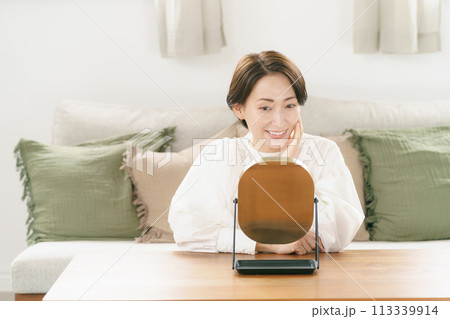 リビングで鏡を見て微笑む女性 リビングで鏡を見て微笑む女性 113339914