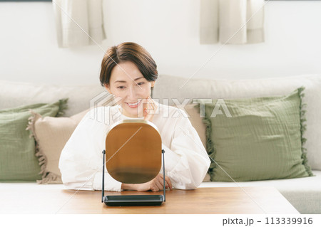 リビングで鏡を見て微笑む女性 リビングで鏡を見て微笑む女性 113339916