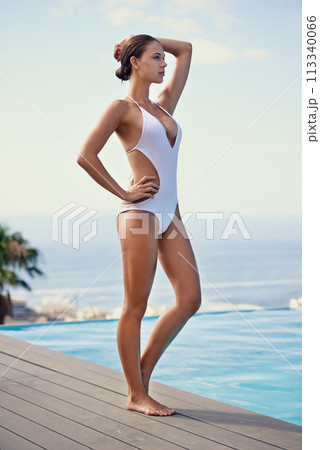 Summer, bikini and woman on deck at pool to relax on luxury holiday or vacation with fashion or swimsuit. Calm, break and person at poolside of hotel, villa or outdoor to enjoy water and sunshine 113340066