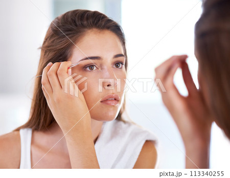 Woman, mirror and eyebrows with tweezers for beauty routine in bathroom for skincare, maintenance or cosmetic. Female person, hand and tool with morning reflection for hair removal, treatment or care 113340255