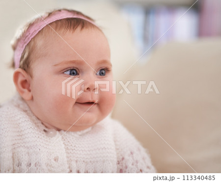 Happy, baby and face in a home with a calm, relax and sweet infant in a living room. Youth, child and house with toddler clothing in the morning ready for a nap on the sofa with joy and headband 113340485