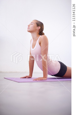 Fitness, pilates and wellness with woman in cobra pose on floor of studio for awareness or mindfulness. Exercise, yoga or zen and confident young person on mat with eyes closed for balance or peace 113341126