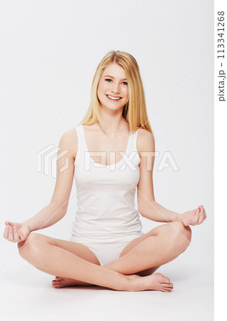 Portrait, meditation and woman in lotus pose in a studio for spiritual, body and mind wellness. Balance, smile and young female person in underwear for zen and relaxing routine by white background. Portrait, meditation and woman in lotus pose in a studio for spiritual, body and mind wellness. Balance, smile and young female person in underwear for zen and relaxing routine by white background. 113341268