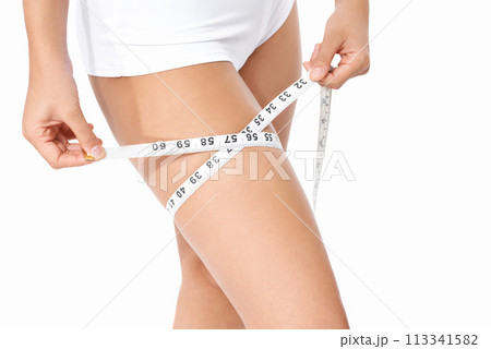 Woman, legs and tape measure for weight loss, slim body or health and wellness on a white studio background. Closeup of female person or model measuring thigh in diet, fitness or healthcare on mockup Woman, legs and tape measure for weight loss, slim body or health and wellness on a white studio background. Closeup of female person or model measuring thigh in diet, fitness or healthcare on mockup 113341582