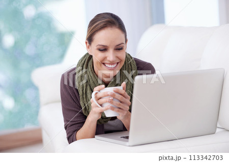 Laptop, relax and happy woman on a sofa with coffee while streaming movie, film or video at home. Pc, smile or female person in a living room with tea, break or social media, subscription or show 113342703