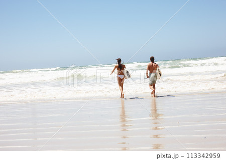 Couple, beach and surfboard for surfing or rear view with waves, adventure and fitness with blue sky. Tourist, people and surfer by ocean in morning for holiday, vacation and freedom in California Couple, beach and surfboard for surfing or rear view with waves, adventure and fitness with blue sky. Tourist, people and surfer by ocean in morning for holiday, vacation and freedom in California 113342959