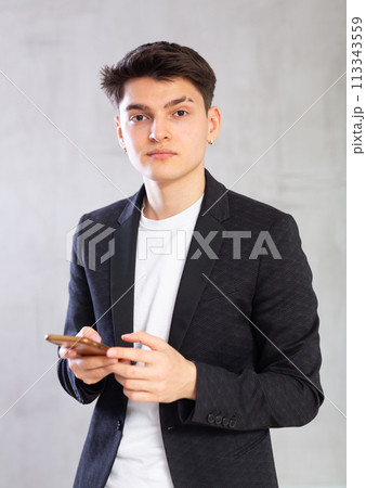 Focused young guy writes message on phone 113343559