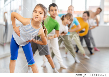 Children do warm-up exercises in studio, prepare for pair dance class 113343674