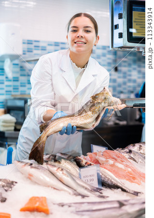 Portrait of saleswoman offering fresh fish atlantic cod at shop Portrait of saleswoman offering fresh fish atlantic cod at shop 113343914