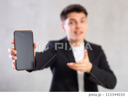 Smiling young guy holding mobile phone in his hand 113344010