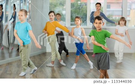 Children training modern dance moves together in studio under the guidance of teacher 113344030