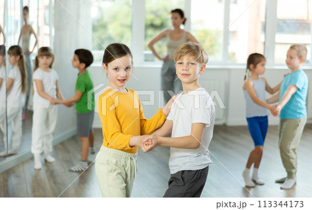 Happy preteen children practicing ballroom dances in pairs in training hall Happy preteen children practicing ballroom dances in pairs in training hall 113344173