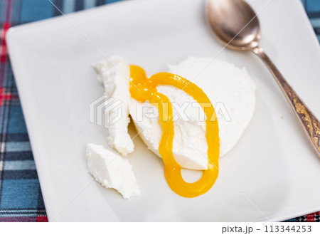 Slice of cottage cheese, filled with large amount of liquid summer honey, is served on plate Slice of cottage cheese, filled with large amount of liquid summer honey, is served on plate 113344253
