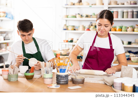 Young woman and young man making pottery Young woman and young man making pottery 113344345
