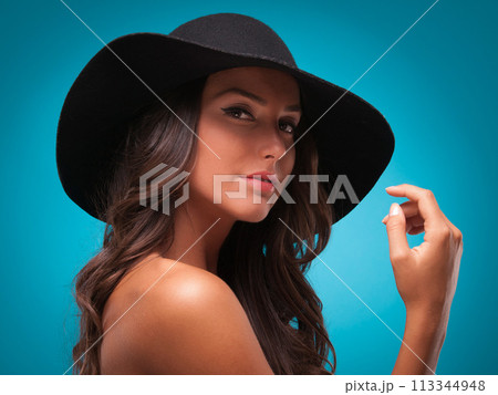 Woman, portrait and beauty in studio, cosmetics and bare shoulders on blue background. Female person, hat and face for dermatology on mockup space, accessories and isolated on backdrop for aesthetic 113344948