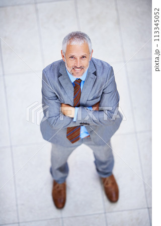 High angle, portrait and happy man with arms crossed in business or office with confidence and pride. Professional, entrepreneur and above person in lobby excited for morning in London at workplace 113345052