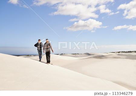 Couple, hiking and sand outdoor or desert with dune, sky and clouds for walking, climbing and move for recreation. Man, woman and young for adventure in weather and dry for season and destination Couple, hiking and sand outdoor or desert with dune, sky and clouds for walking, climbing and move for recreation. Man, woman and young for adventure in weather and dry for season and destination 113346279