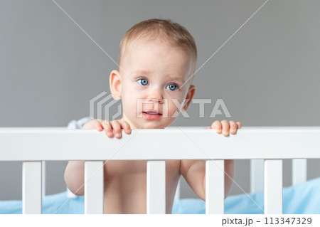 The baby pulls himself up on the back of the crib with little effort 113347329