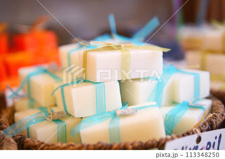 A stack of white soaps with blue ribbons in a basket A stack of white soaps with blue ribbons in a basket 113348250