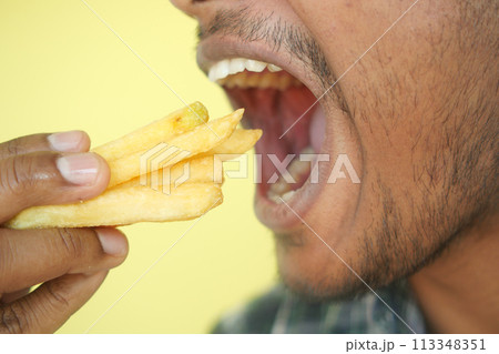 hungry man eating fries closeup hungry man eating fries closeup 113348351