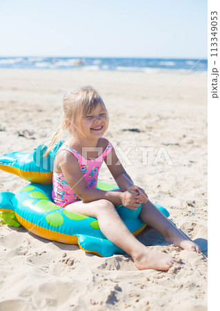 Happy girl sitting and laughing on an inflatable crocodile toy at the beach sunny day 113349053