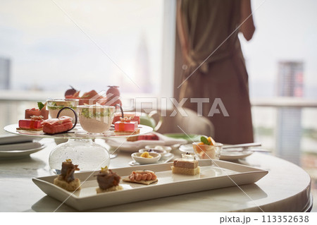 asian woman looking at view through window while enjoying room service 113352638