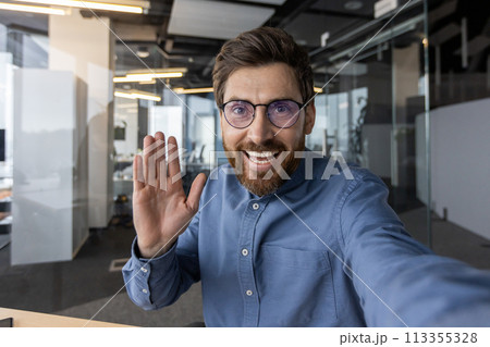 A welcoming professional male greeting with an open hand in a well-lit, contemporary office setting, conveying openness and friendliness. A welcoming professional male greeting with an open hand in a well-lit, contemporary office setting, conveying openness and friendliness. 113355328