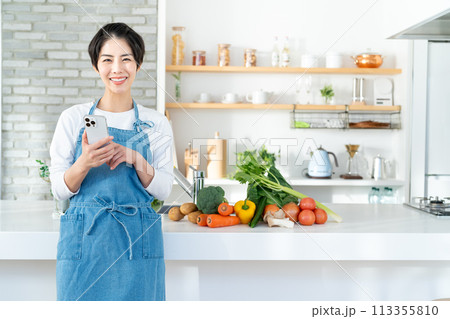 キッチンに立つ笑顔の若い女性 113355810