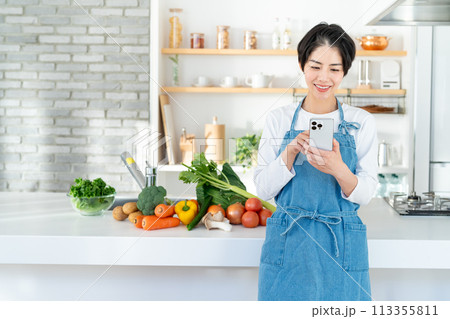 キッチンに立つ笑顔の若い女性 113355811