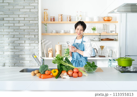 キッチンに立つ笑顔の若い女性 113355813