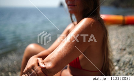 Woman beach sea. Women's legs by the sea and women's hands are smeared with sunscreen. Slow motion video of a beautiful woman smearing sunscreen. Summer travel holidays vacation on the sea. 113358085