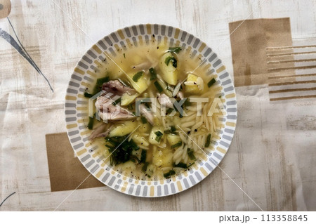 Bowl of traditional chicken soup served in a white plate on background tablecloth. Close-up Bowl of traditional chicken soup served in a white plate on background tablecloth. Close-up 113358845