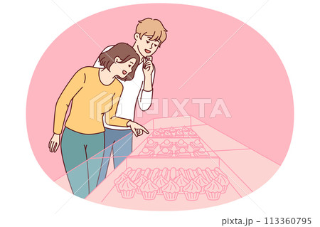 Young couple stands near showcase of pastry shop with cakes and desserts under transparent glass 113360795