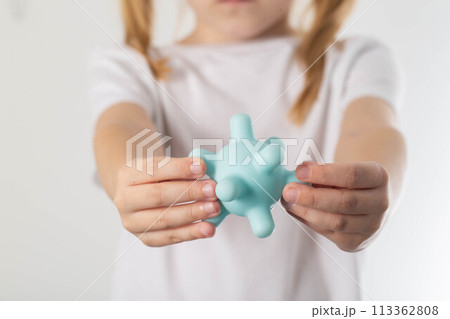 A blonde girl holds a model of a virus in her hands. Concept of ARVI and influenza virus in children, close-up 113362808